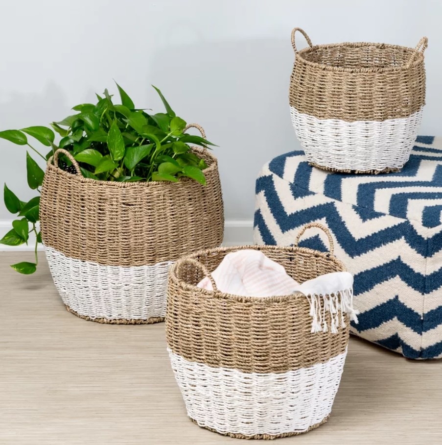 Set of 3 white and tan rattan baskets displayed on wooden floor.