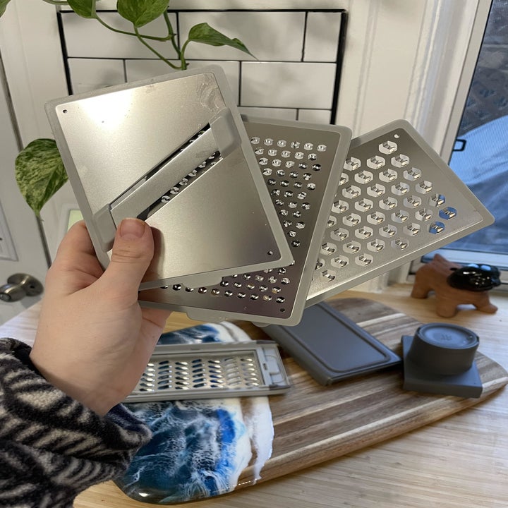 A person holding three of the grating sheets over top of a cutting board