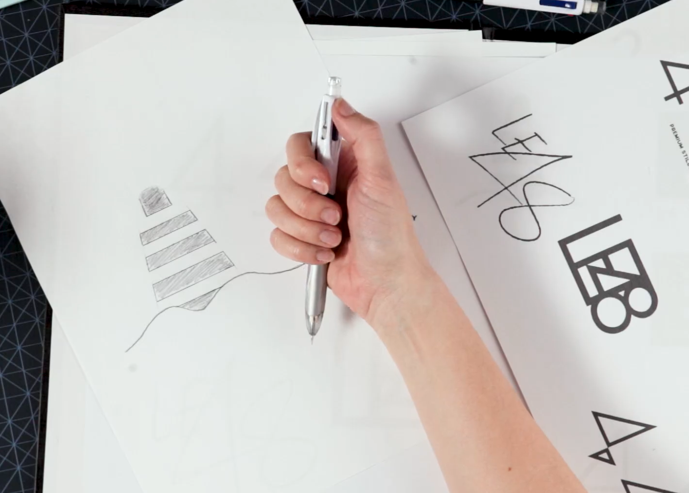 A person holding the pen over a bunch of scattered papers