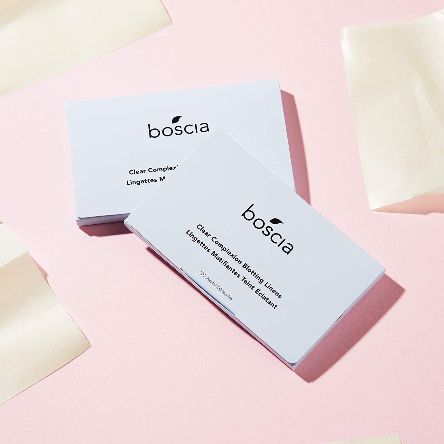 Two packs of blotting sheets on a plain background