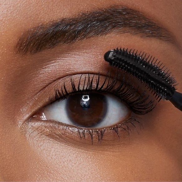 Model using mascara on eye lashes