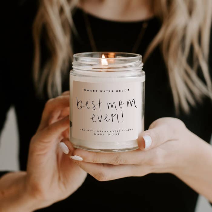Person holding a lit pink candle with &quot;best mom ever!&quot; on it