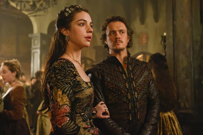 Mary, Queen of Scots, holds the arm of Gideon Blackburn as they stand in a crowded ballroom