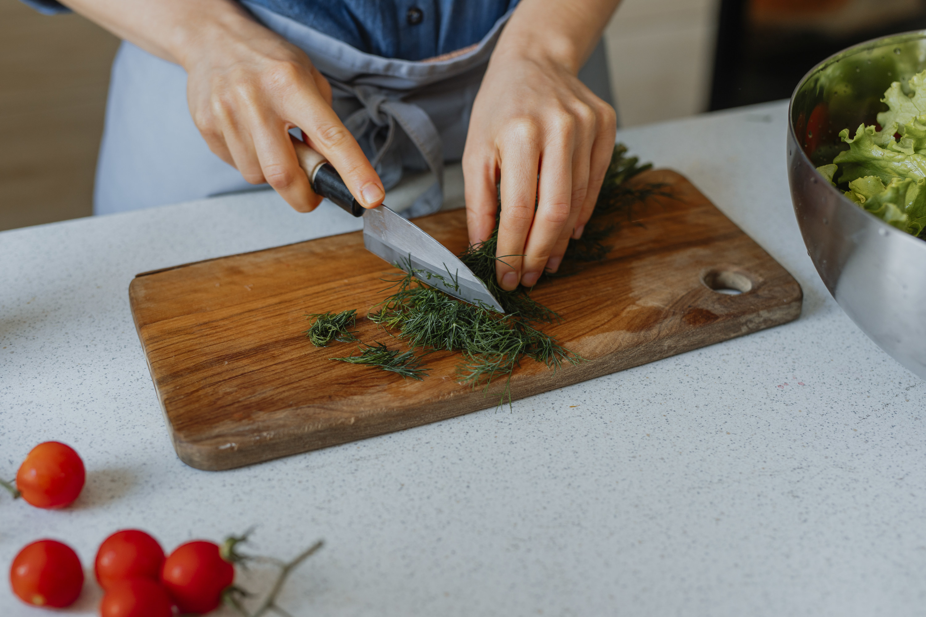 A person&#x27;s hands chopping dill