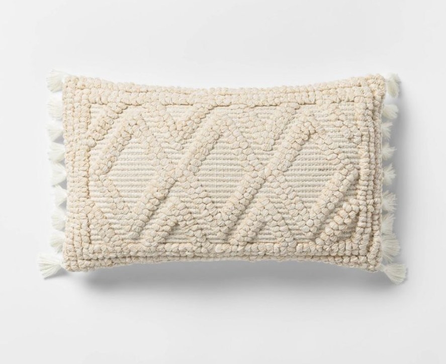 Cream throw pillow with woven detailing and tassels 
