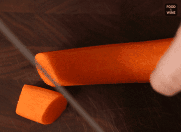 A person&#x27;s hands slicing carrots