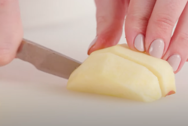 A person using a paring knife to cut an apple