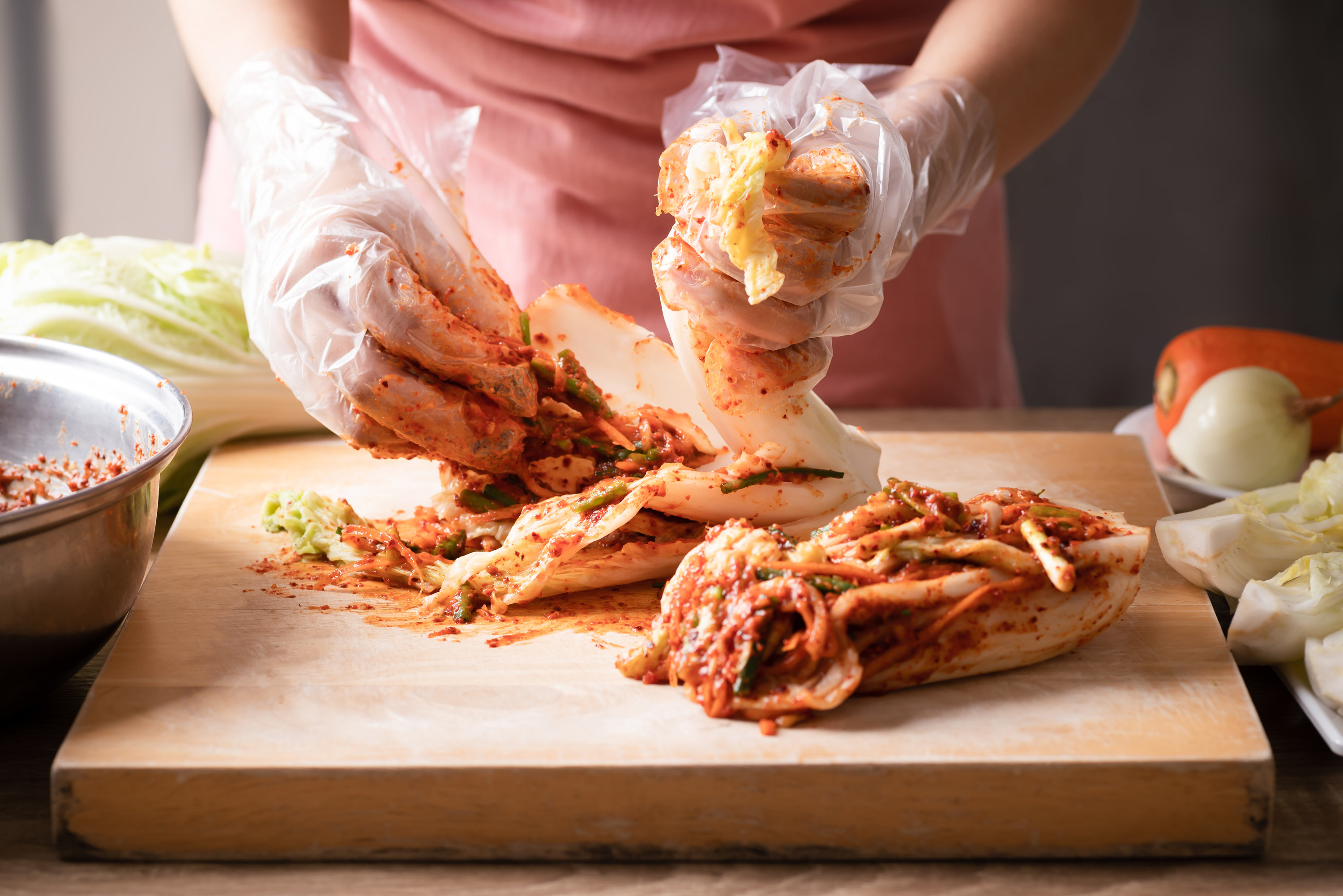 A person handling kimchi with gloves on