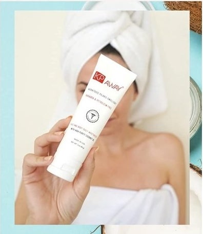 Model wearing towel on body and head holding the bottle of lotion in front of her face