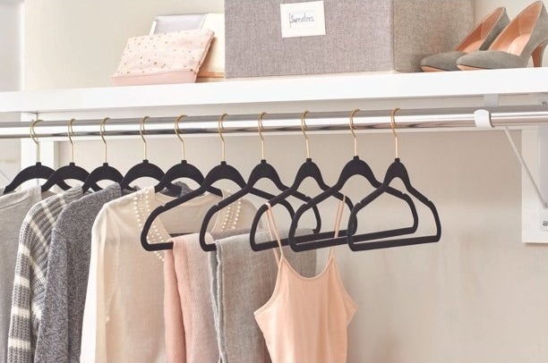 the black velvet hangers hanging in a closet, some with clothes and some empty