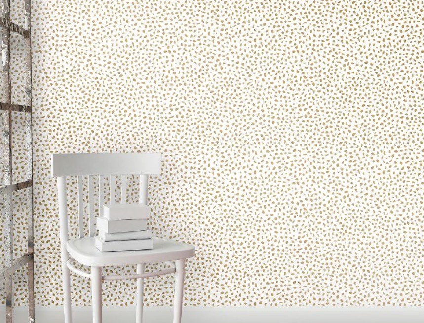 Gold dotted peel and stick wallpaper with a white chair in foreground.