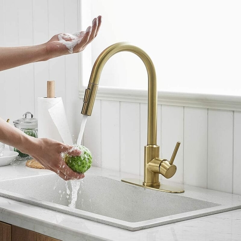 A person uses the touch functionality on the brushed gold faucet