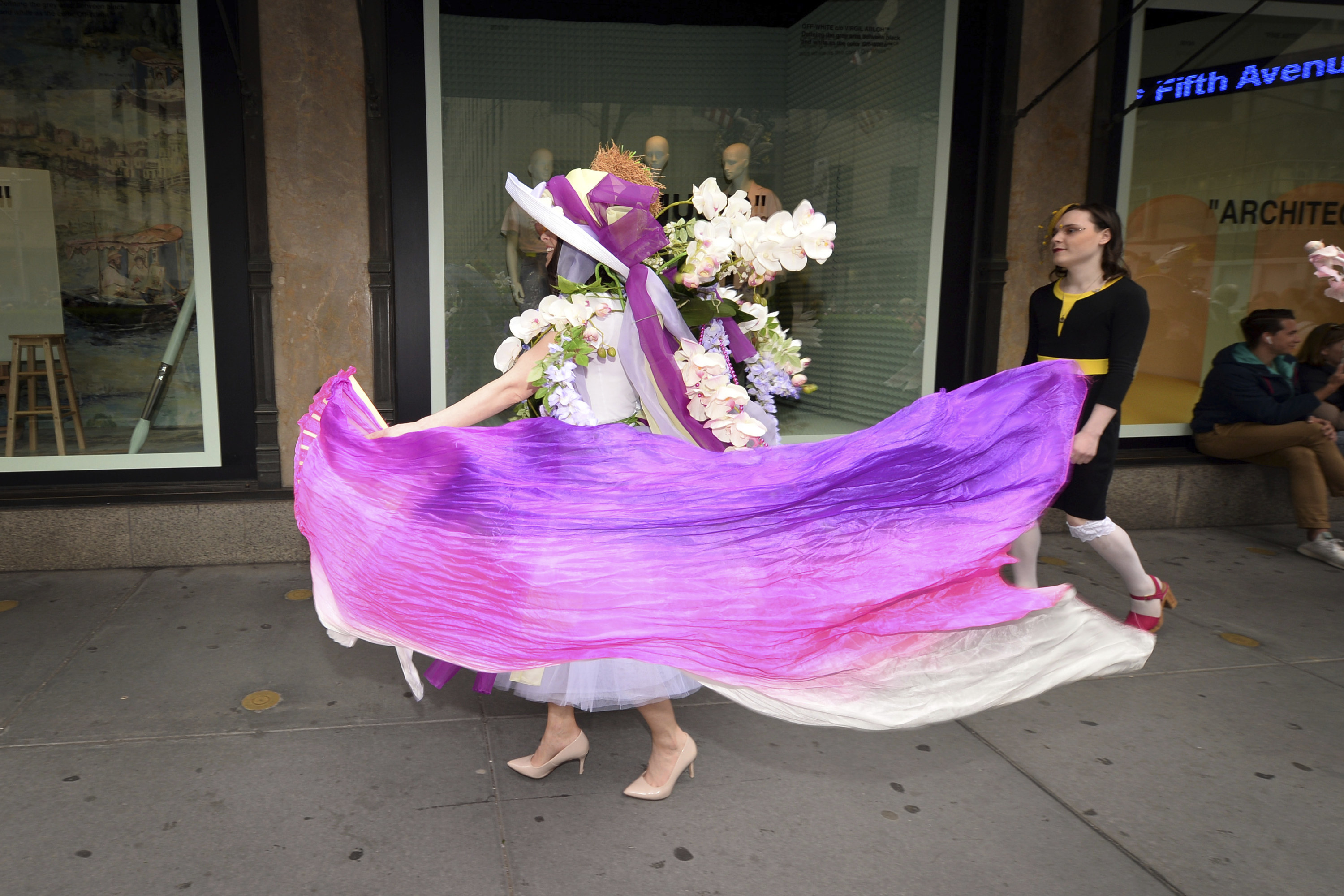 A woman wearing a large hat with flowers swirls around