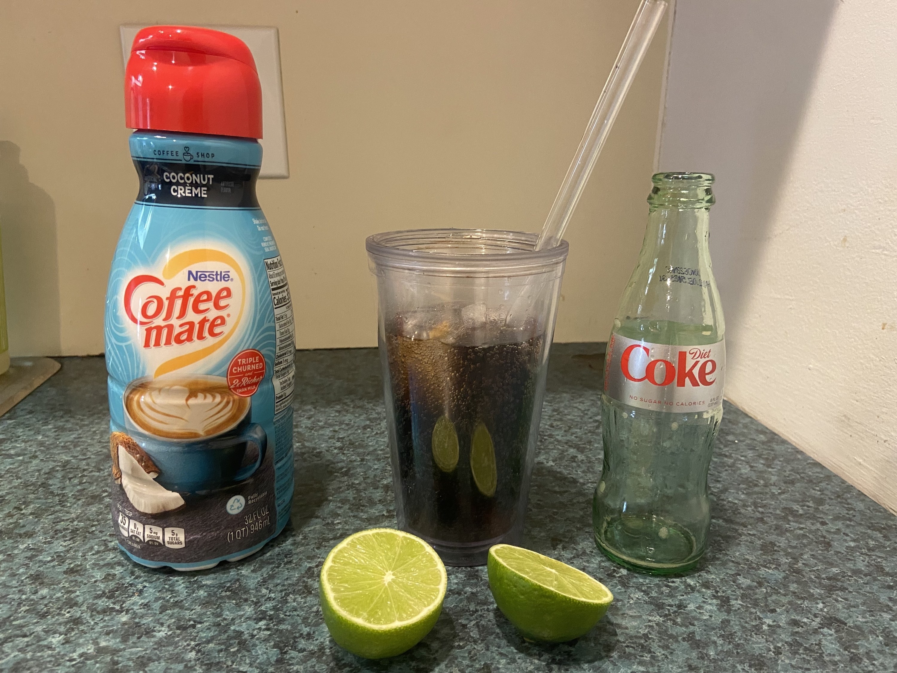 Creamer, Diet Coke, a cup with ice, and a lime cut in half on a countertop