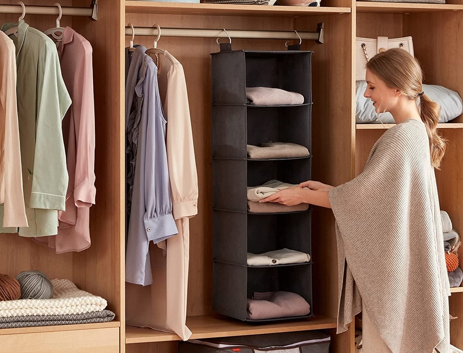 model putting folded clothes on one of the shelves of the organizer