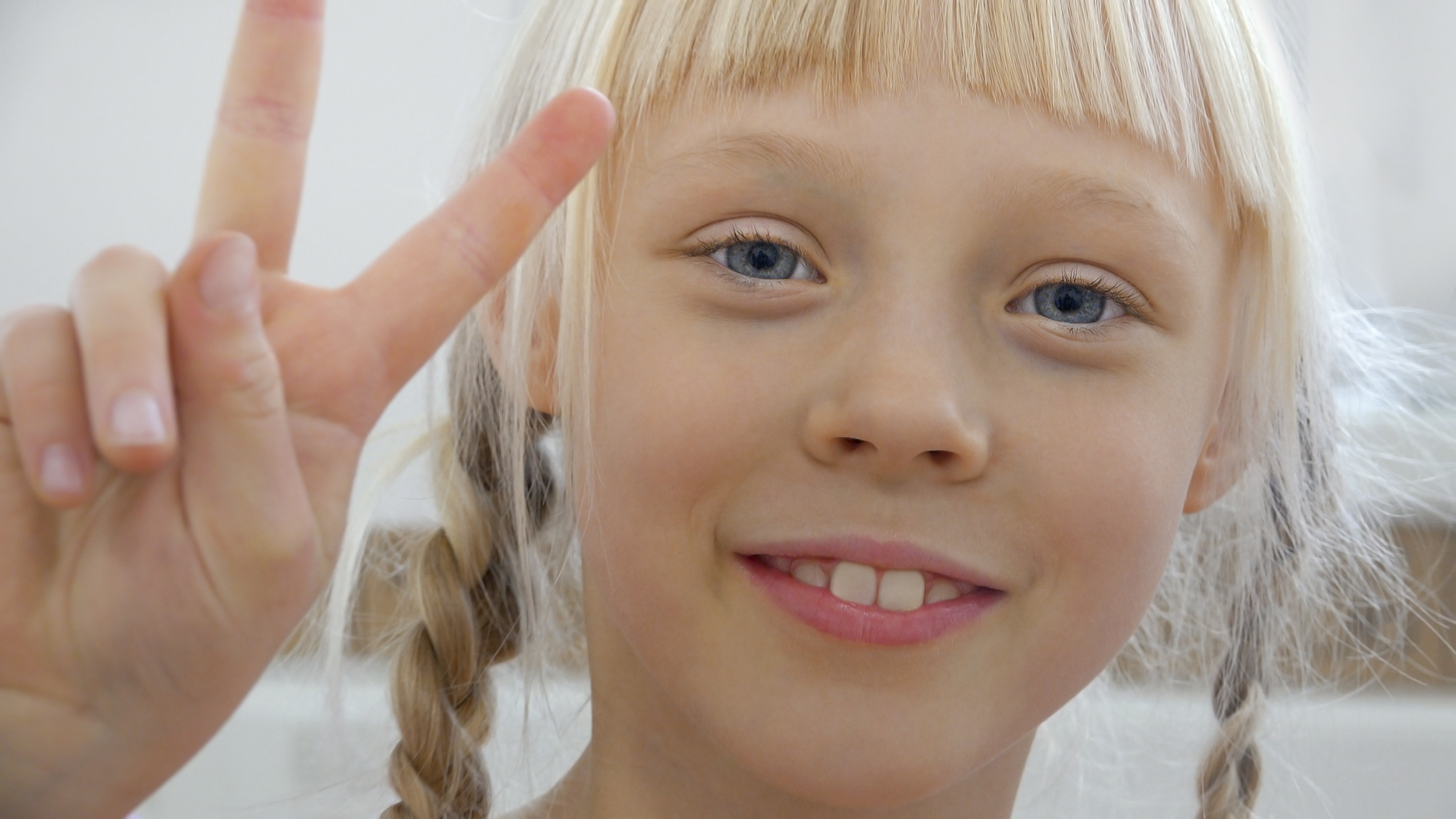 Little white girl with blonde hair doing a peace sign