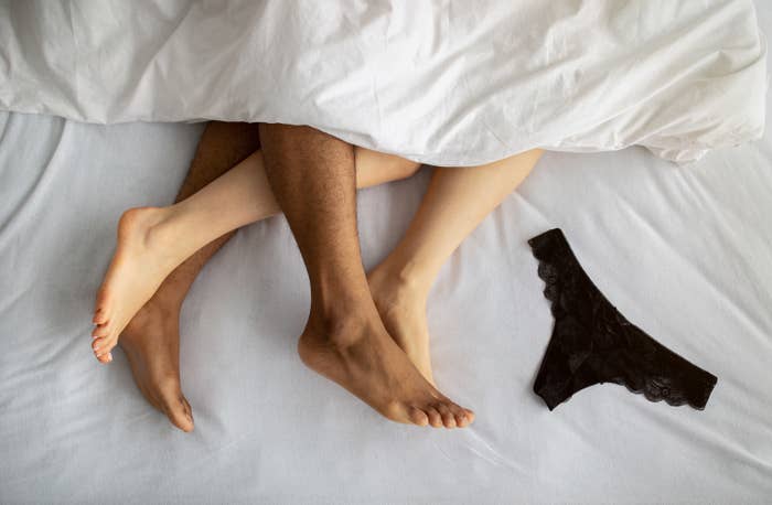 A couple&#x27;s bare feet alongside underwear on a bed