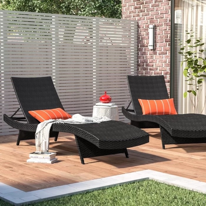 black wicker loungers with orange pillows on wood patio