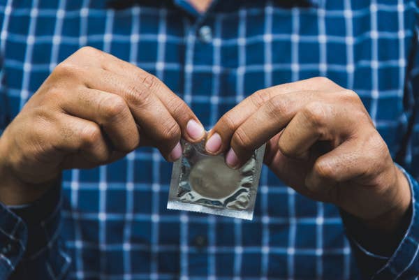 Two hands opening a condom