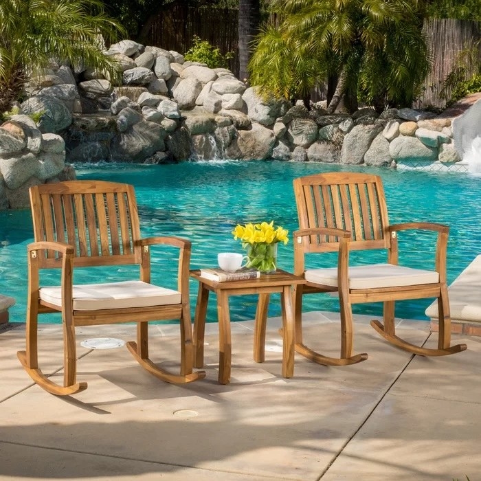 acacia wood rocking chairs and table by a pool