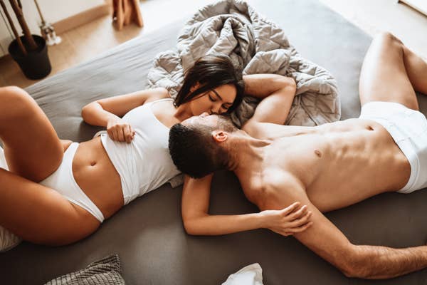 A man and a woman lying in bed kissing