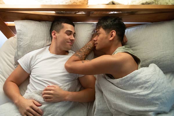 Two men lying in bed together
