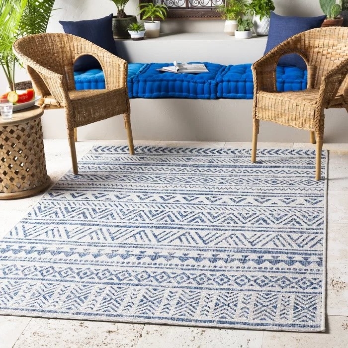 blue and white geometric patterned rug beneath two wicker chairs