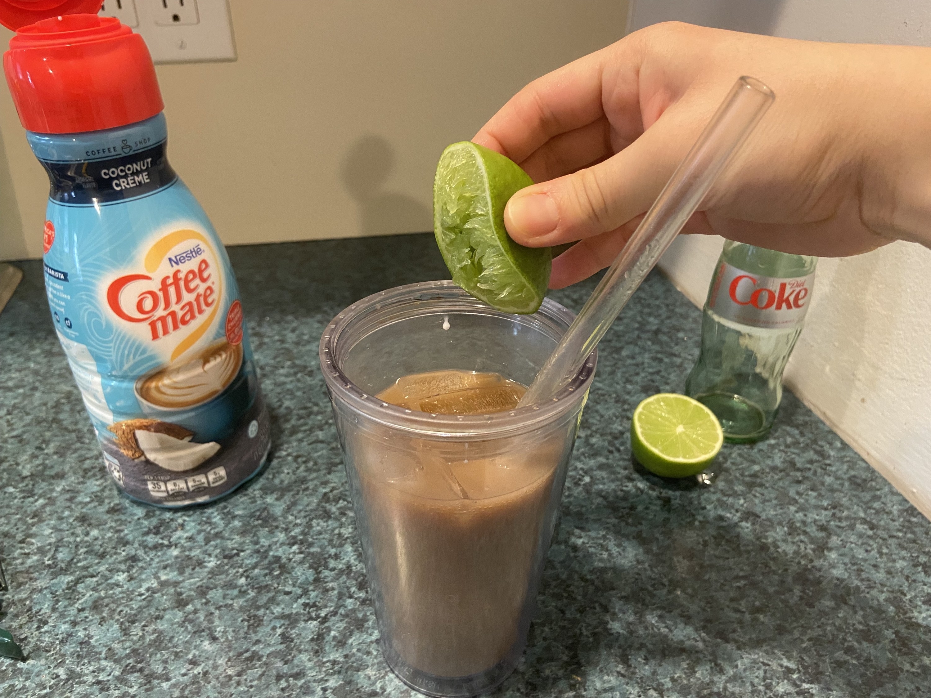 The author squeezing half a lime into her glass of diet coke and coffee creamer