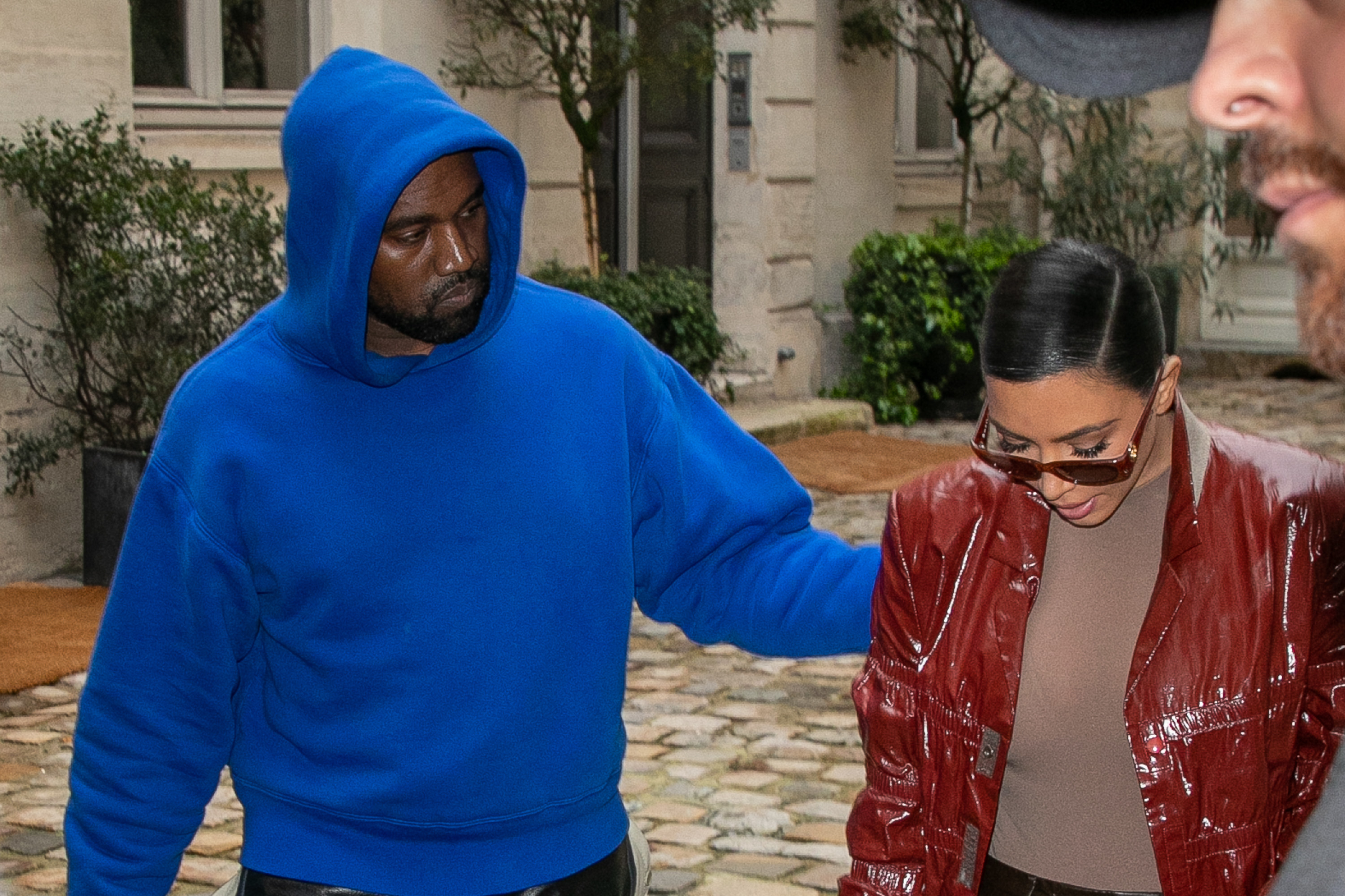Kanye and Kim walk next to each other as he puts his hand on her shoulder