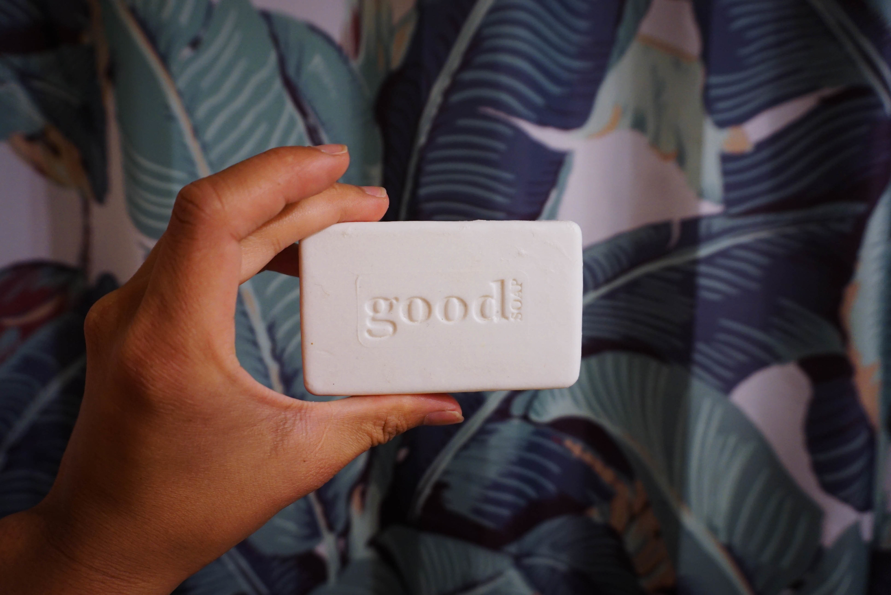 hand holding the bar of soap that says Good on it