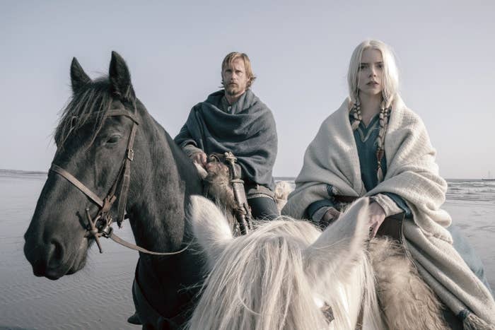 Alexander Skarsgård and Anya Taylor-Joy on horsebacks near a river