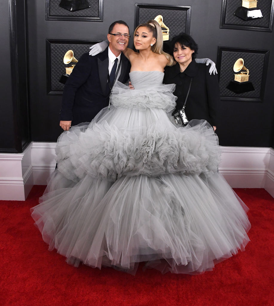 Ariana in a long tiered strapless gown hugs her parents on the red carpet
