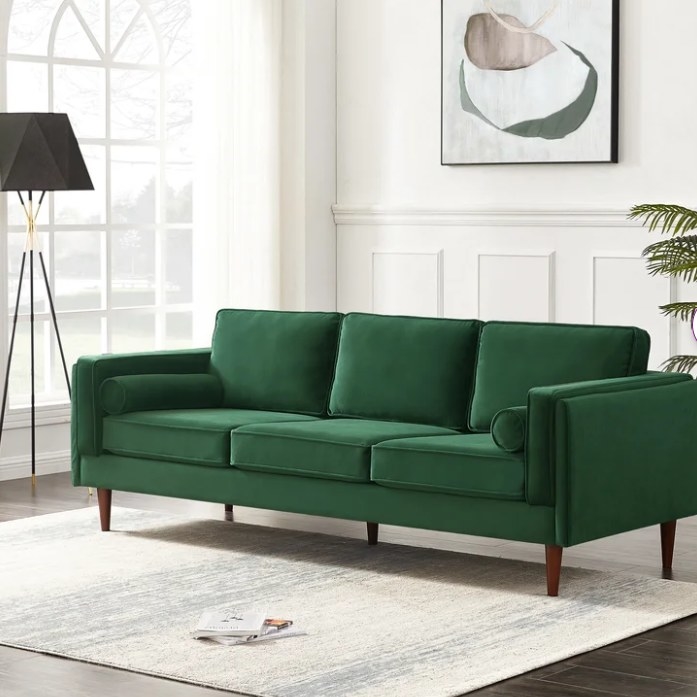 Green velvet couch in a neutral living room.