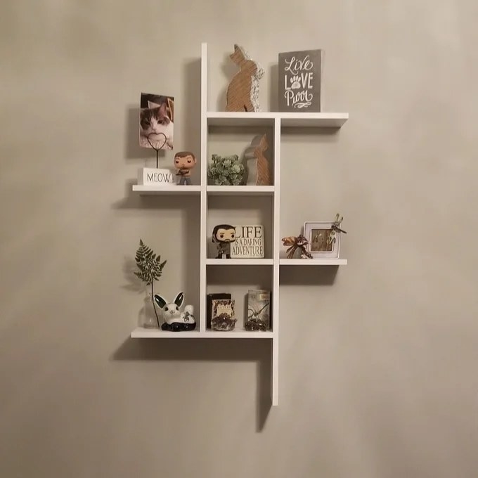 A wall shelf with 3 tiers of shelves in white