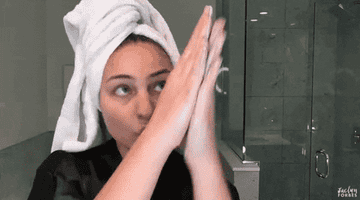 A woman in a robe and towel rubbing her hands together
