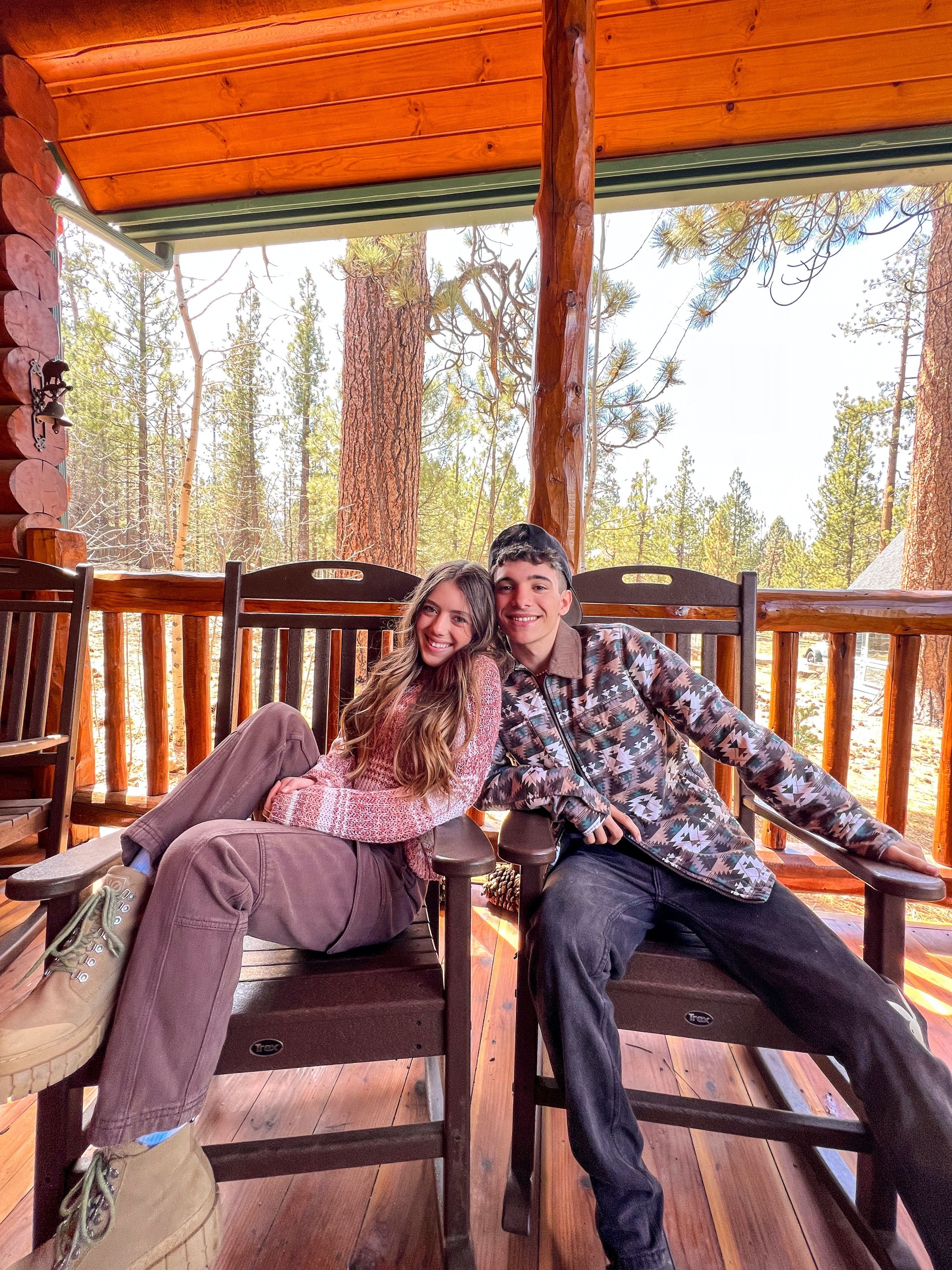 A young couple sitting on chairs outside smiling at a the camera