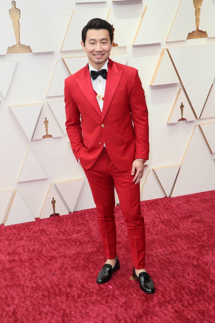 Simu Liu in a red suit on a red carpet
