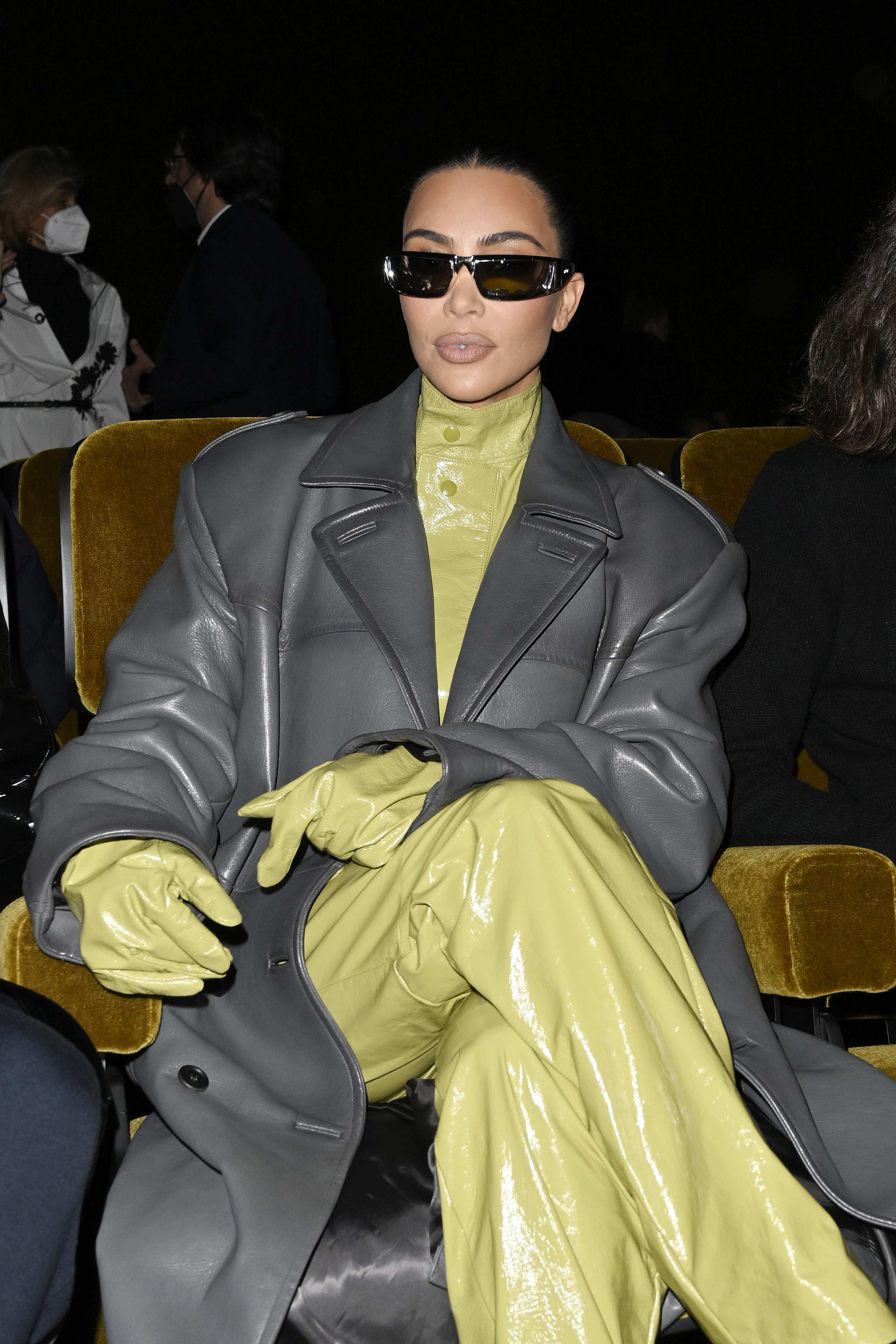 Kim Kardashian sits cross-legged in a velvet chair