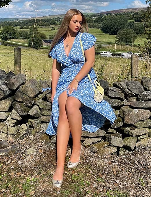 A person sitting on a rocky fence wearing the wrap dress with flats