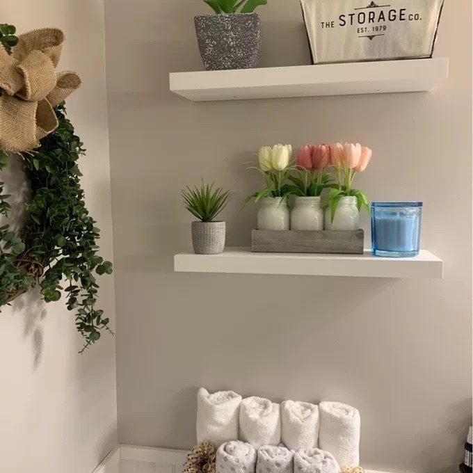 two floating wall shelves in white with plants and other decor on them