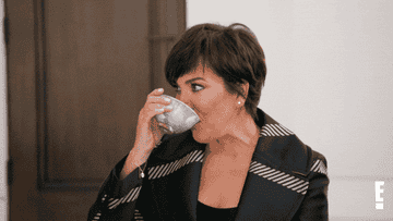 Kris Jenner taking a sip from a teacup and pretending to take a smoke from her fingers