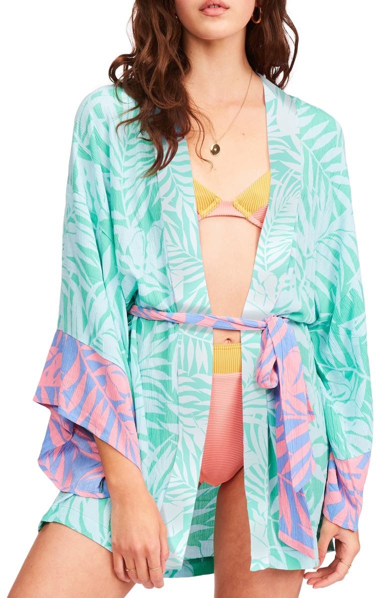 A woman wearing the palm frond-printed robe over a bikini