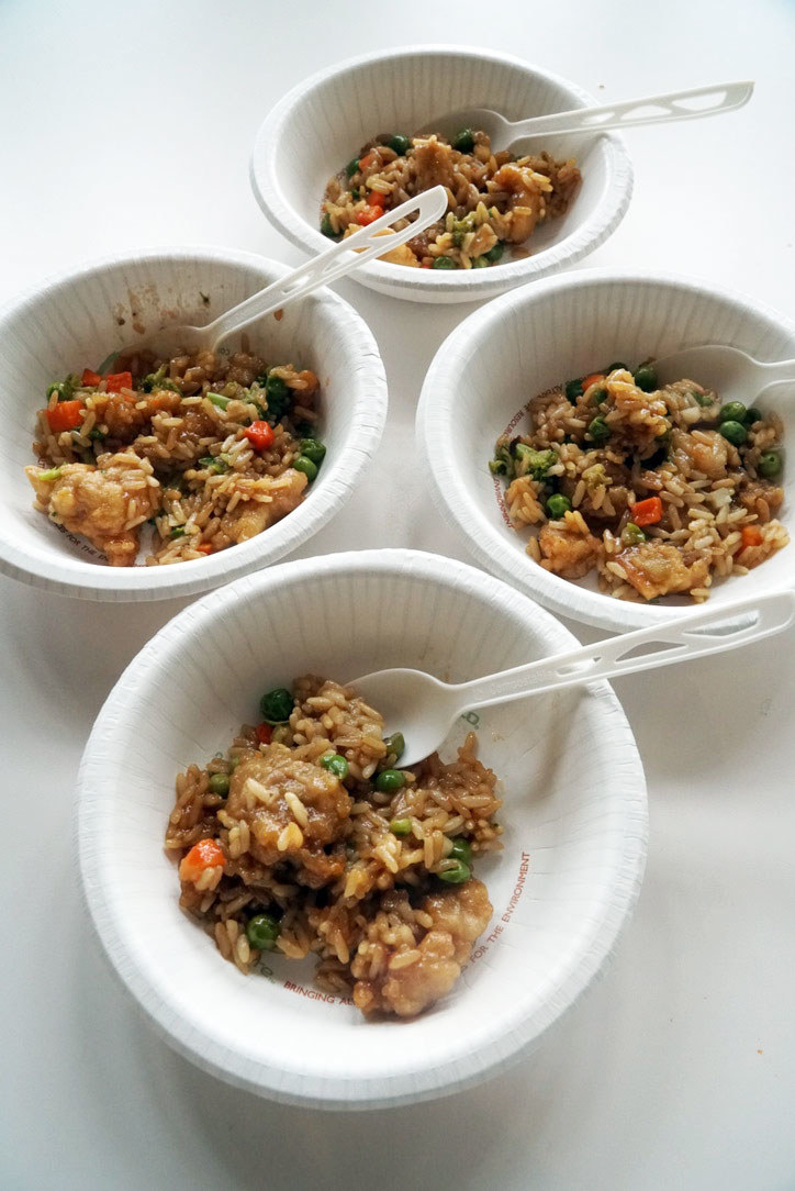 Four white bowls of Mandarin Orange Chicken over vegetable fried rice