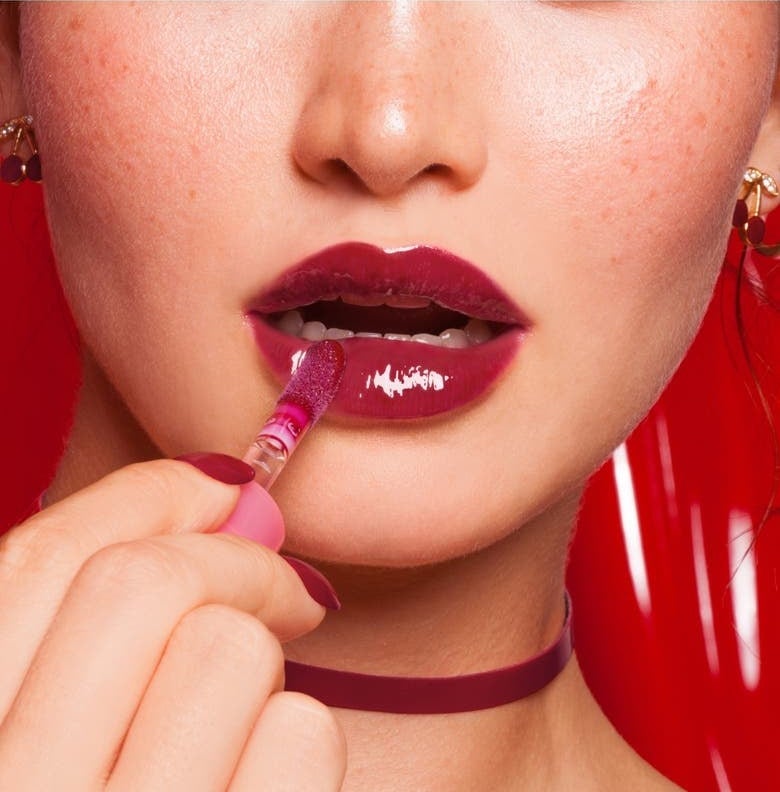 A person applying deep red lip gloss