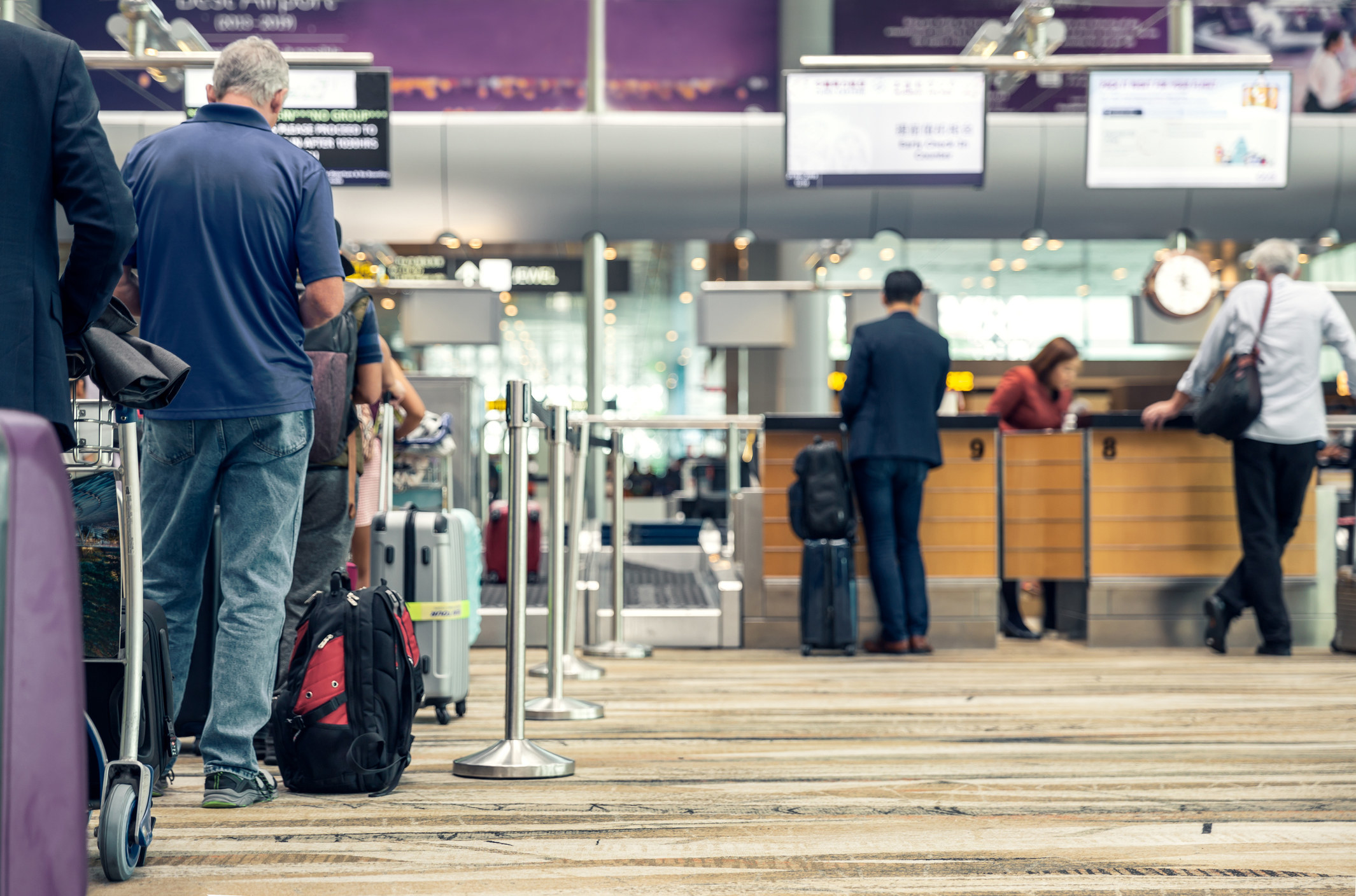 A group of people waiting in line to check their bags at the airport.