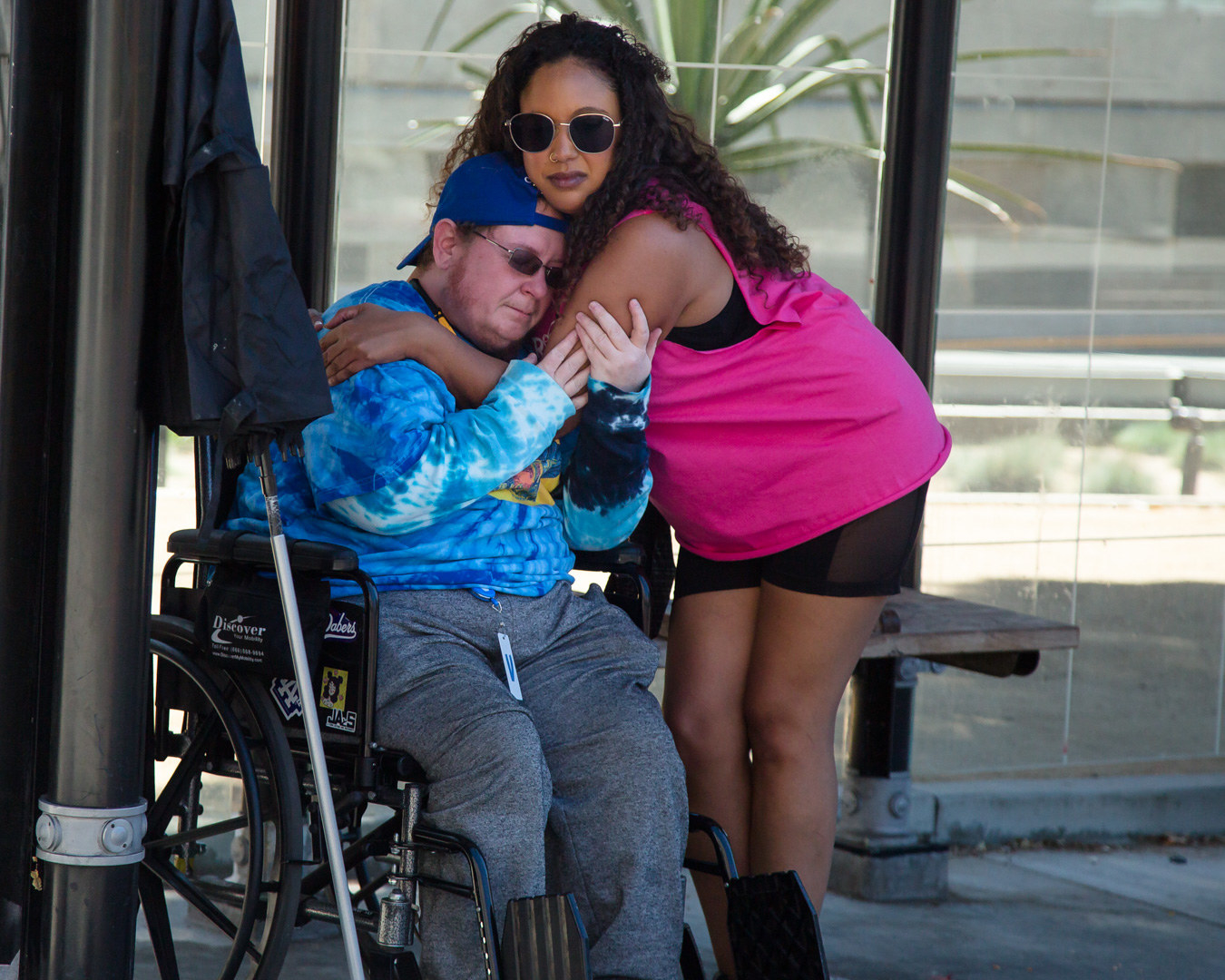 A person in a wheelchair and a person who is standing embrace