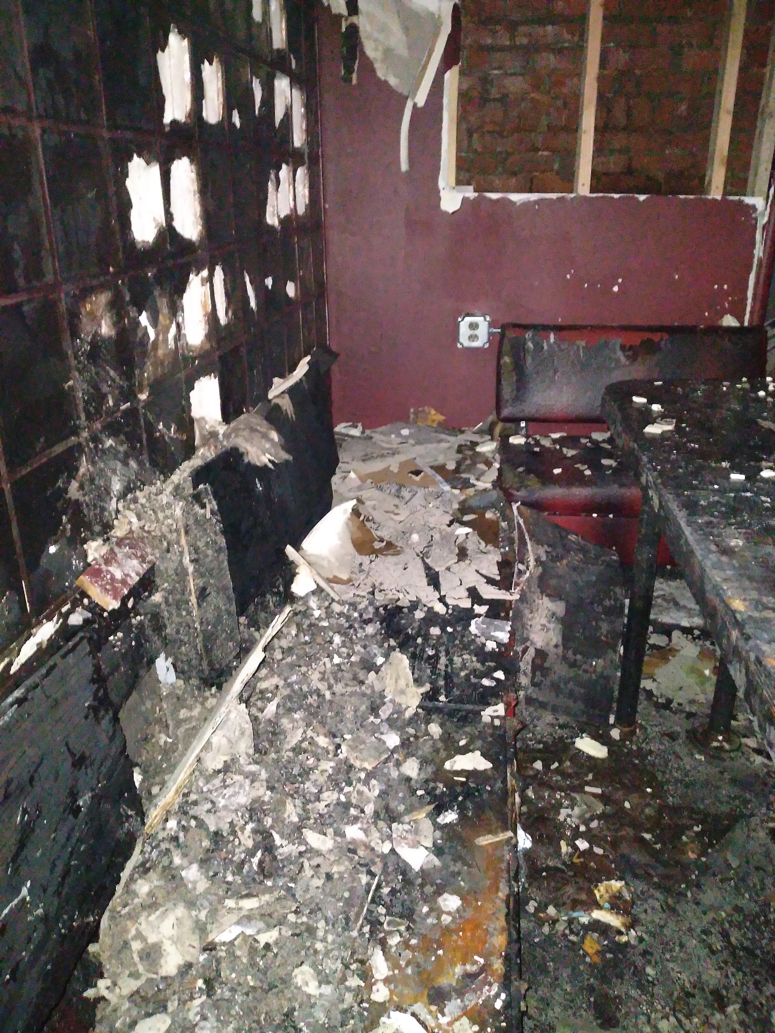 A corner of the bar&#x27;s interior is burned with debris everywhere and parts of the window broken