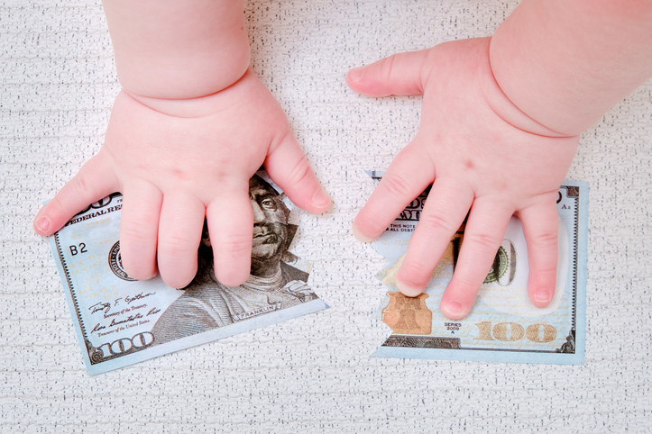 Baby hands covering a $100 bill torn in half