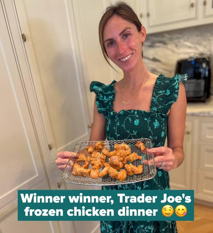 A woman holding an air fryer rack topped with breaded chicken