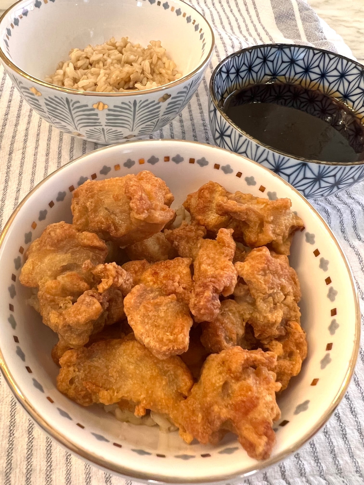 A bowl of crispy chicken next to a bowl of rice and sauce